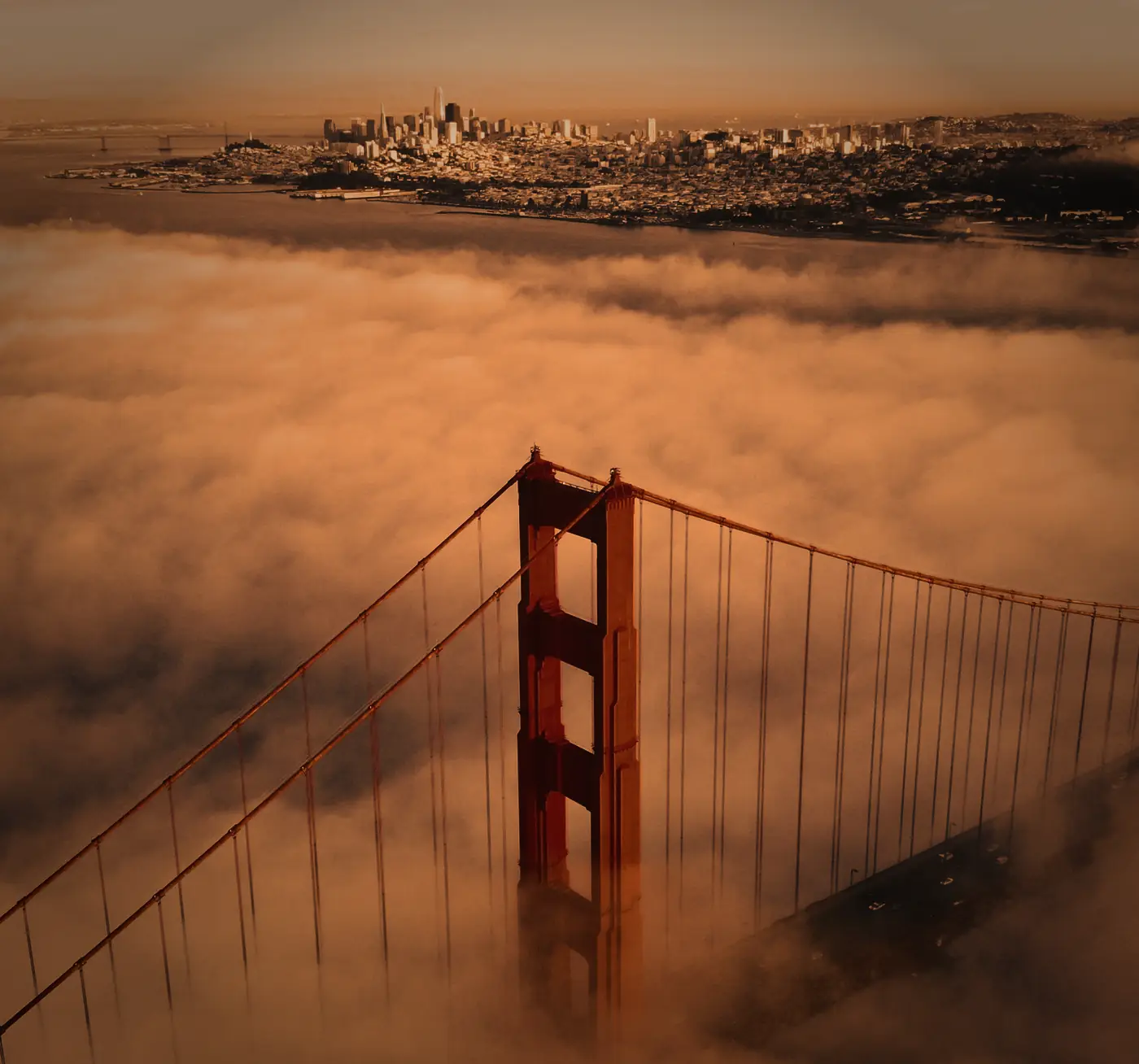 The Golden Gate Bridge rising out of the fog, with San Francisco behind it